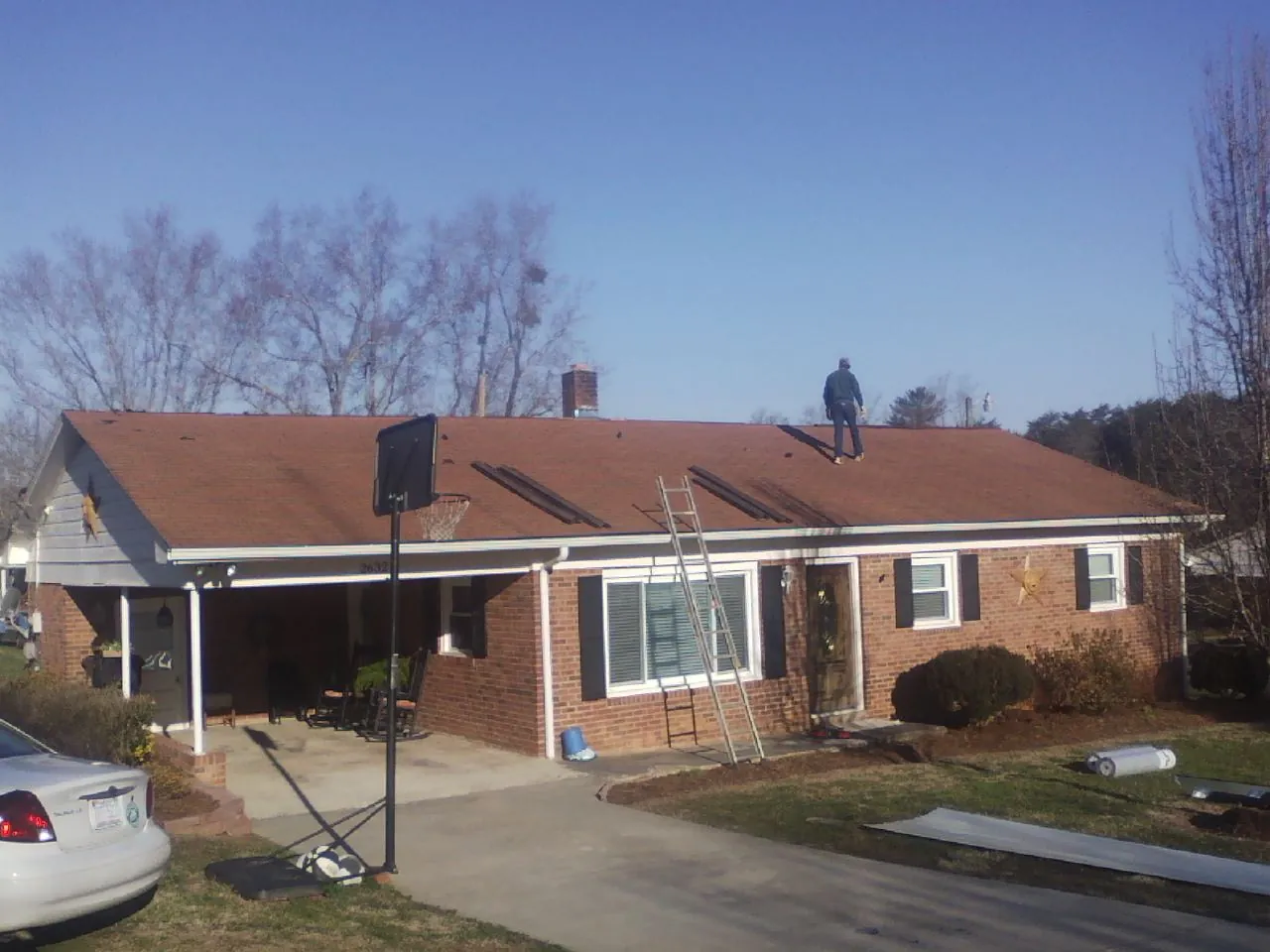Roofer stripping a shingle roof on a brick ranch before metal panels in East Aurora
