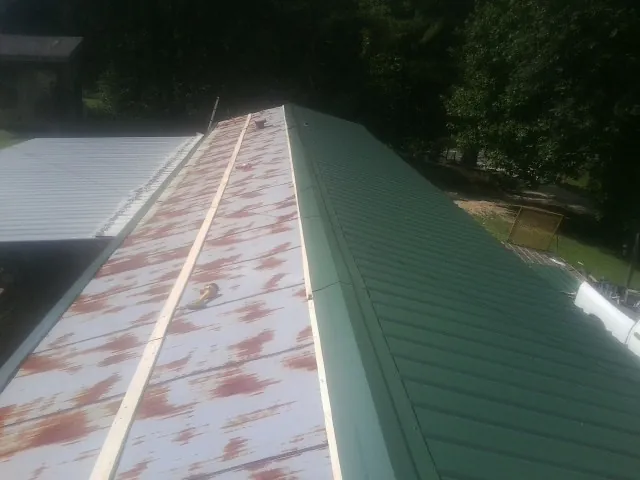 Old rusted panels beside newly installed green metal roofing — Wind Damage Roof Repair by Roofing Brothers in East Aurora