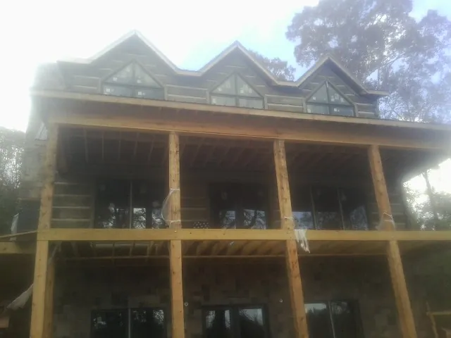 Dormers and porch framing on a large log home under construction — Roof Coating work by our crew in East Aurora