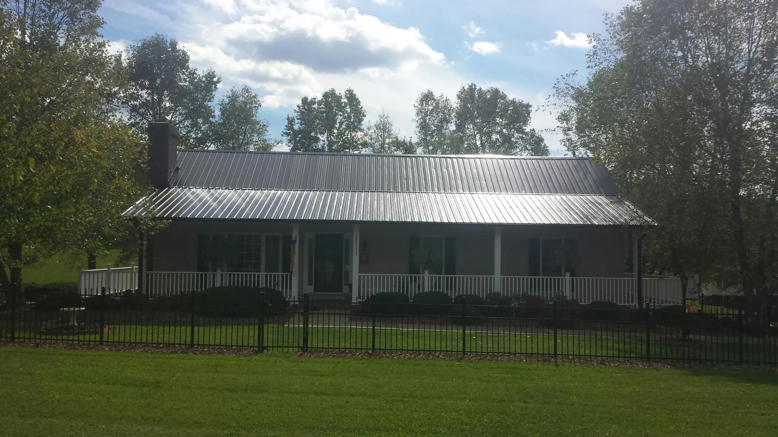 Gray metal roof on a brick ranch with a full width front porch — Gutter Guard Installation work by our crew in East Aurora