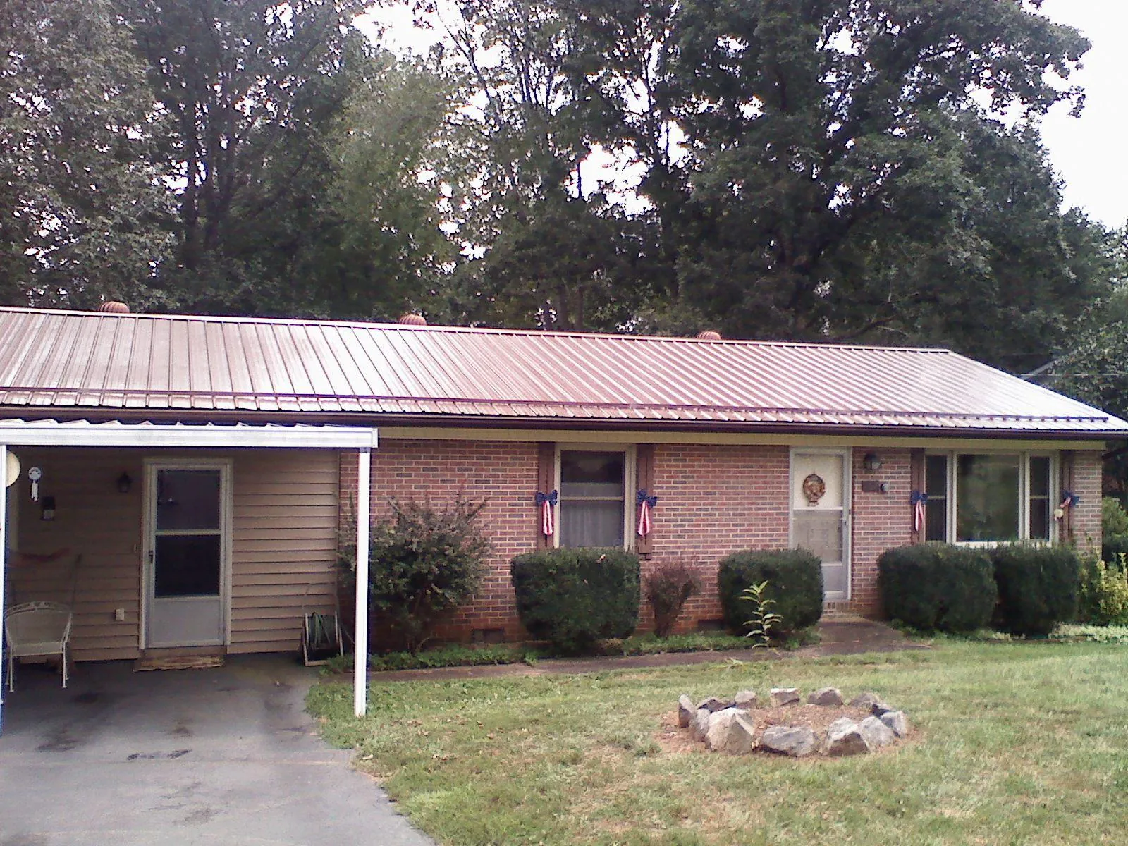 Bronze metal roof and carport on a brick ranch home — Roof Repair work by our crew in East Aurora