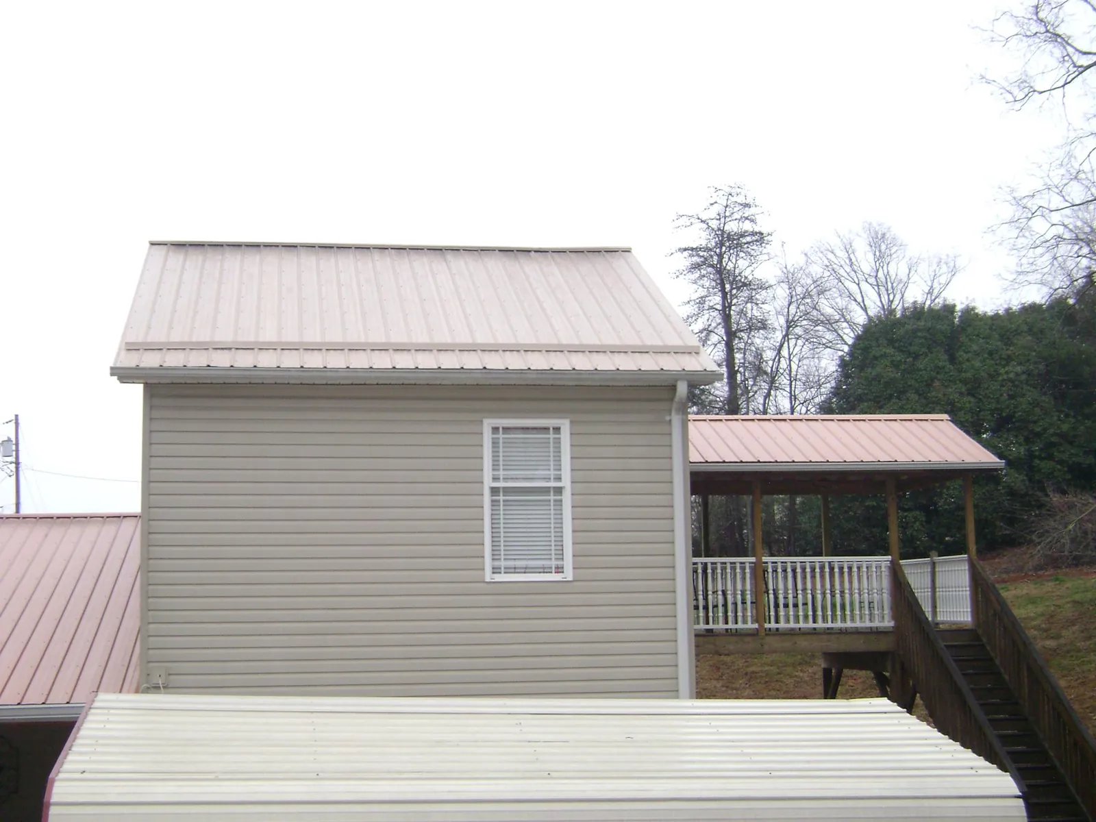 Tan metal roofs on a two story addition and attached porch, from a Roof Replacement job in East Aurora