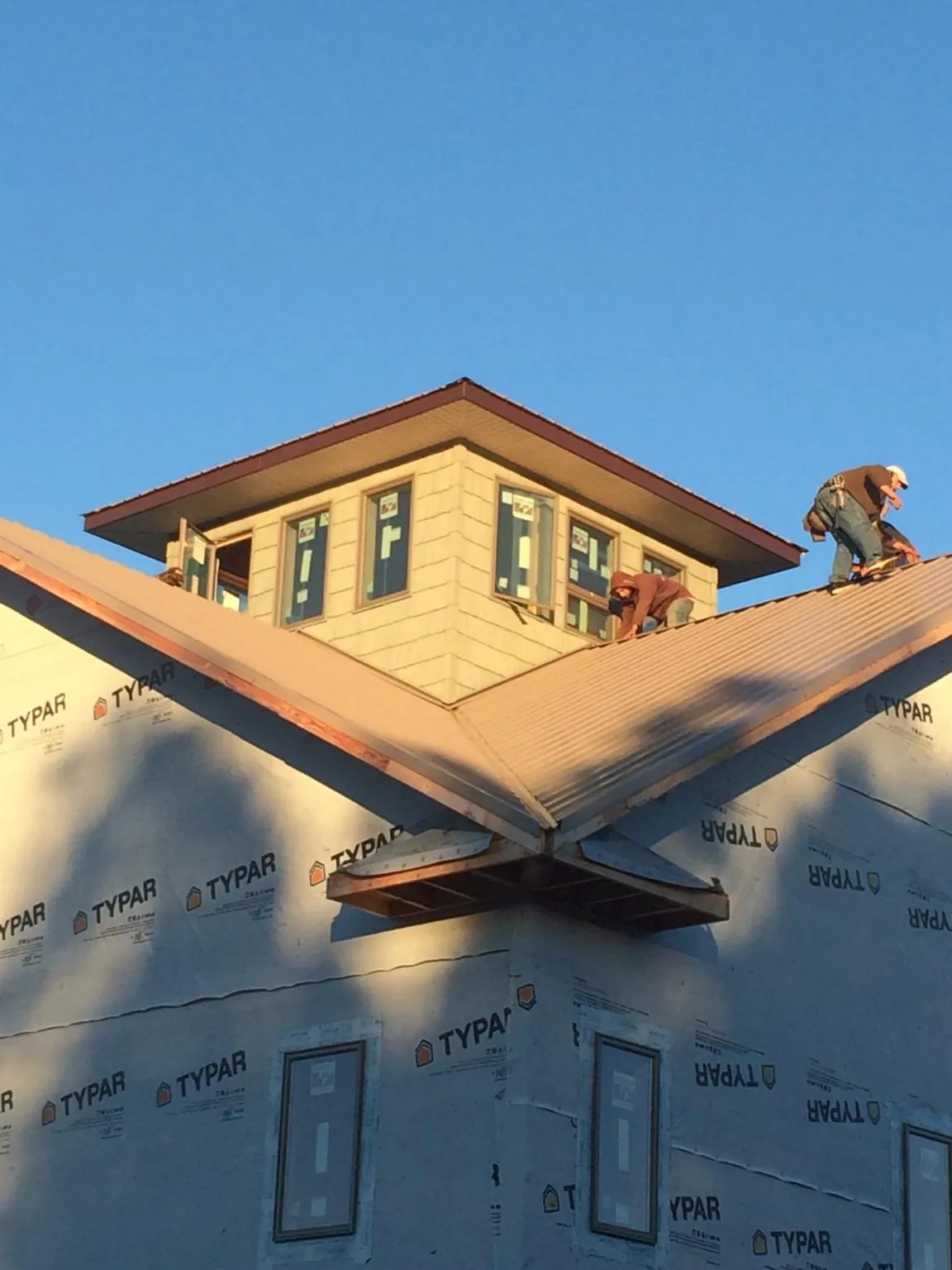 Roofers working around a rooftop cupola on a new metal roof at sunset — Roof Waterproofing in East Aurora by Roofing Brothers